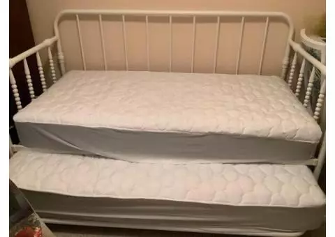 White rod iron trundle bed with two twin sized mattresses